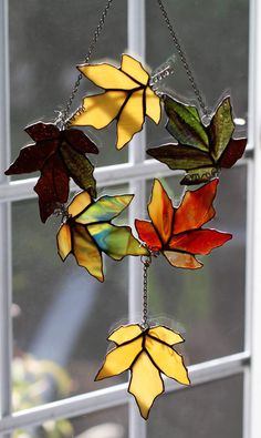 a wind chime hanging from a window in front of a leaf - shaped decoration