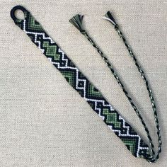 two green and white bracelets sitting on top of a cloth covered table next to a pair of scissors