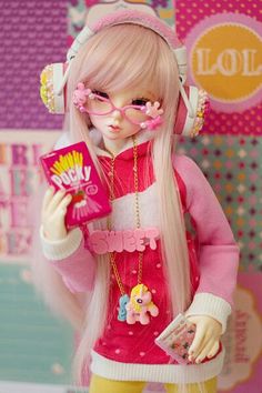 a doll with long blonde hair wearing headphones and holding a pink package in her hand