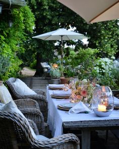 an outdoor dining area with wicker chairs and white table cloths set for dinner