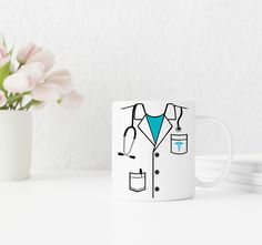 a coffee mug with a doctor's coat on it next to a flower vase