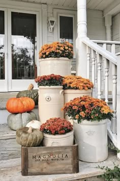 a bunch of potted flowers sitting on top of a wooden crate in front of a house