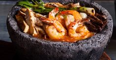 a bowl filled with shrimp and vegetables on top of a wooden table