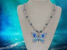 "Butterfly Necklace - Pearl Necklace - Jeweled Necklace - Jeweled Butterfly Necklace - One Of A Kind Necklace - Statement Necklace - Gift This necklace measures 23 1/2\" in length.  This necklace is comprised of teal glass pearls, silver metal bead caps, silver acrylic divider beads, silver acrylic multifaceted round beads, and a silver metal butterfly with blue winds and teal glass jewels and one black glass jewel.  This necklace is strung on beading wire with a lobster clasp for closure.  This Jeweled Necklace, Teal Glass, Metal Butterfly, Metal Bead, Different Shades Of Pink, Jewel Necklace, Jasper Necklace, Necklace Pearl, Pretty Necklaces