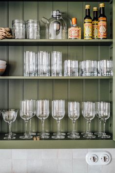 many empty wine glasses are lined up on the shelf