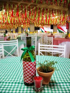 a green and white checkered table cloth with red candle holders on it next to a wine bottle