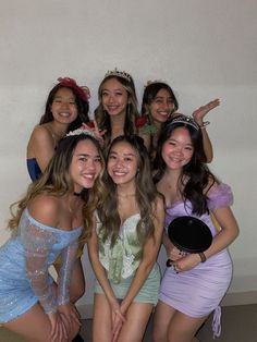 a group of young women posing for a photo in front of a white wall with one woman wearing a tiara