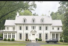 a car parked in front of a large white house with trees and grass around it