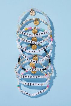 a stack of bracelets with words written on them and charms hanging from the side