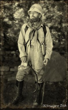 an old photo of a man with a bow and arrows in his hands, standing outside