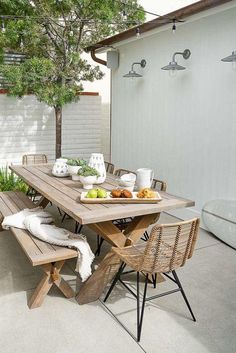 a wooden table sitting on top of a cement floor next to a white fence and trees