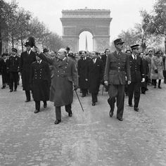 an old photo of men in uniform walking down the street