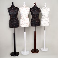 three mannequins are standing next to each other on wooden bases with black and white tops