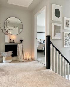 a hallway with pictures on the wall and candles in front of an open door that leads to a bedroom