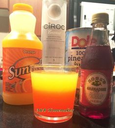 an orange drink sitting on top of a counter next to bottles