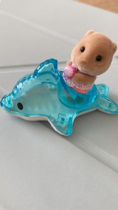 a small stuffed animal sitting on top of a plastic dolphin