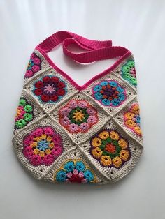 a crocheted purse is displayed on a white surface with a pink strap around it