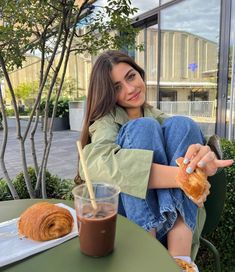 a woman sitting at a table with a doughnut and coffee in front of her