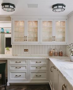 a kitchen with white cabinets and marble counter tops