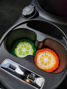 two crocheted oranges are placed in the center of a car cup holder