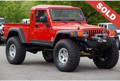 a red jeep is parked in a parking lot