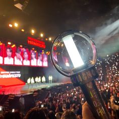 a hand holding a magnifying glass in front of a crowd at a concert