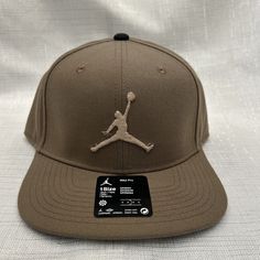 Elevate your style with this Air Jordan Brown Jumpman Hat Snapback Cap for Men. Featuring the iconic Jumpman logo, this adjustable hat is made of high-quality polyester and canvas fabric that is perfect for any season. The classic sports and logo theme of this hat makes it a great choice for casual and travel occasions. The versatile design of this snapback cap makes it suitable for any outfit. Whether you're a fan of the Jordan brand or simply looking for a stylish and comfortable accessory, th Sports Flat Bill Hat In Brown, Brown Flat Brim Baseball Cap For Sports, Brown Flat Bill Sports Hat, Brown Flat Brim Snapback Hat For Sports, Brown Flat Brim Sports Hat, Sporty Brown Snapback Hat, Adjustable Flat Brim Dad Hat For Sports, Brown Snapback Hat For Sports With Curved Bill, Adjustable Snapback Hat For Baseball Season