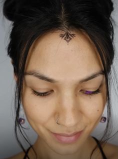 a woman with her eyes closed and tattoos on her forehead