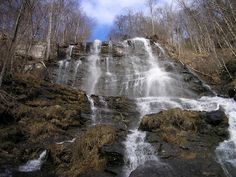 there is a waterfall in the middle of the woods with water cascading down it