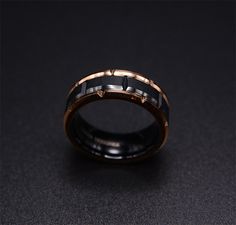 a black and gold wedding ring on a dark surface