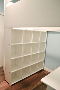 an empty room with white shelving and wood flooring