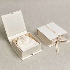 an open white box with a bow on the top and ribbon around it, sitting on a gray surface