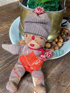 a knitted doll sitting on top of a plate next to a potted plant