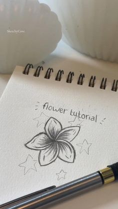 a notepad with a flower on it next to a pen