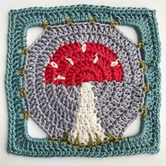 a crocheted square with a red and white tree on it in the center