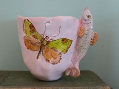 a ceramic cup with a butterfly and fish on it