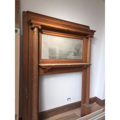 an old fashioned fireplace in a room with white walls and wood trimming on the mantle