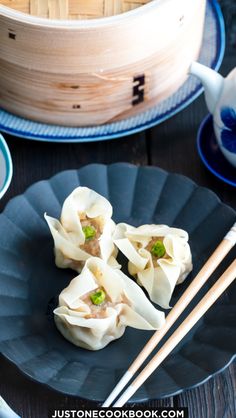 some dumplings are on a black plate with chopsticks