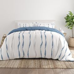 a bed with blue and white comforters in a room next to a potted plant