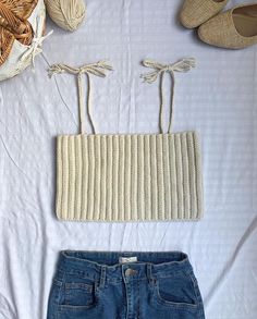 a pair of shorts, sweater and shoes are laid out on a bed with white sheets