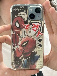 a man holding up his phone case with the spiderman cover in front of him