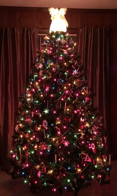 a brightly lit christmas tree in front of a window