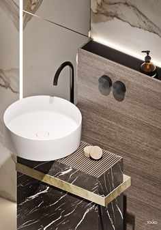 a modern bathroom with marble counter tops and black faucet, along with a round sink