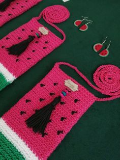 a pink crocheted bag with tassels and other accessories on a green surface