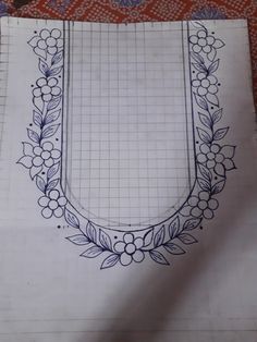 a piece of paper with a drawing of a wreath and flowers in it on top of a table