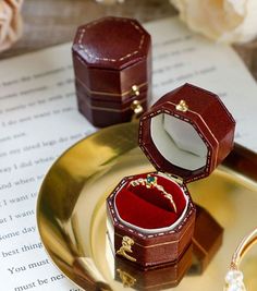 an open ring box sitting on top of a gold plate