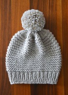 a white knitted hat sitting on top of a wooden floor