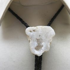 This very cool  white geode bolo tie was handmade in our very own Montana Rock Shop, Rockin JK Designs.  The bolo slide measures 1 3/8ths inch tall and 1 1/2 inches wide across the top. The black leatherette string tie measures 36 inches long with shiny silverplated metal end caps. You have the option of replacing the leatherette cord tie for a leather one if you choose.   We will send this to you in a lovely gift box for easy gift giving.   If you like vintage bolo ties, vintage costume jewelry Handmade Adjustable Unique Bolo Ties, Unique Handmade Adjustable Bolo Ties, Unique Adjustable Bolo Ties For Gifts, Unique Adjustable Bolo Ties, Unique Adjustable Bolo Tie For Gift, Unique Adjustable Lariat Bolo Ties, Handmade Unique Bolo Ties, Kalispell Mt, Cord Ties