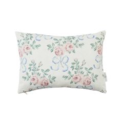 a white pillow with pink and blue flowers on the front, sitting against a white background