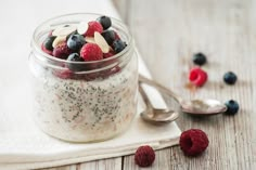 a glass jar filled with fruit and nuts on top of a white napkin next to spoons